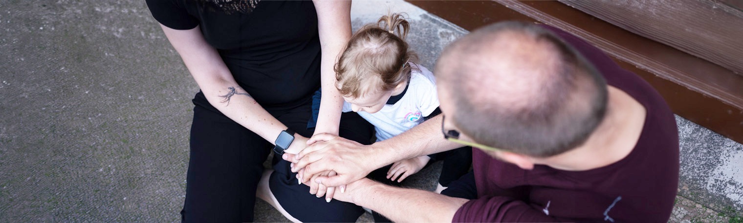 Eltern- und Familienberatung, Mutter, Vater, Kind legen die Hände übereinander