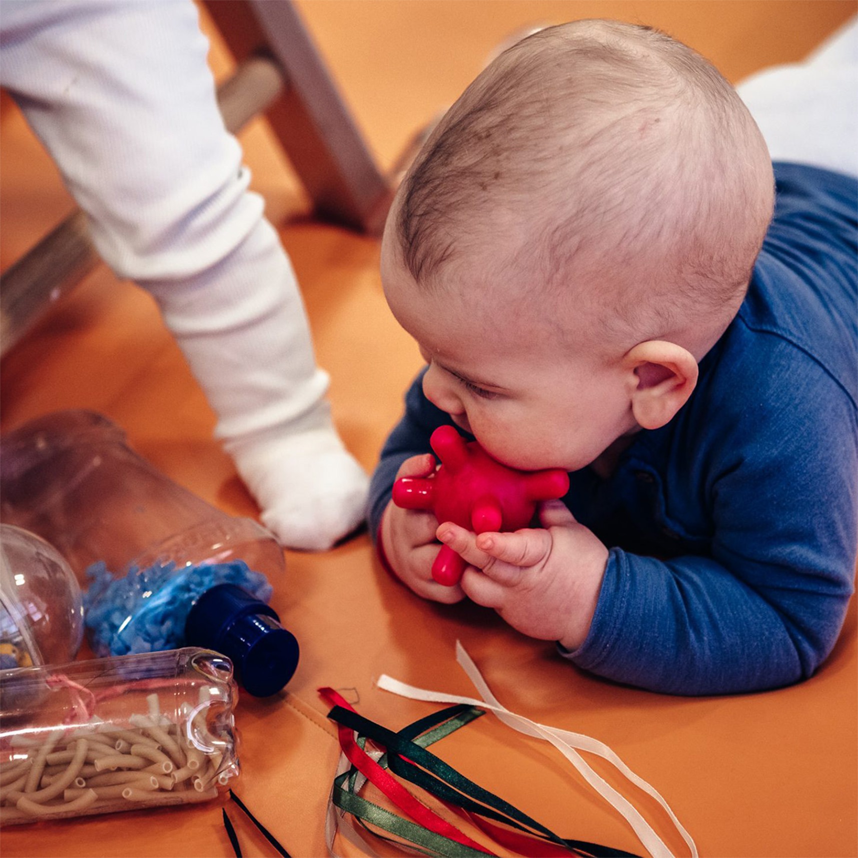 Kind spielt mit roter Kugel im Mund, wachsam